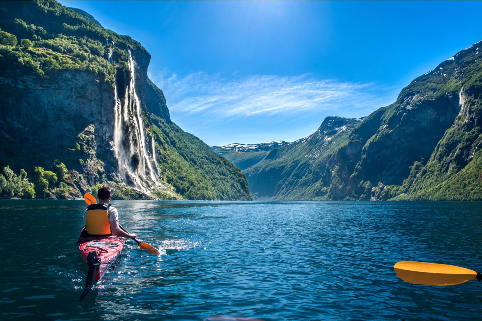 young man kayaking along the fjord geiranger enjoying the waterfall